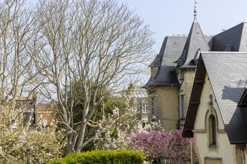 Mansion victorienne de l'Hôtel De Lion Sur Mer avec fleurs printanières et arbres nus à Lion sur Mer, France