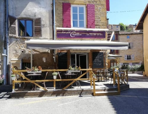 Terrasse du restaurant Le petit Châtillon avec balustrades en bois, tables et chaises dans une charmante place de village français