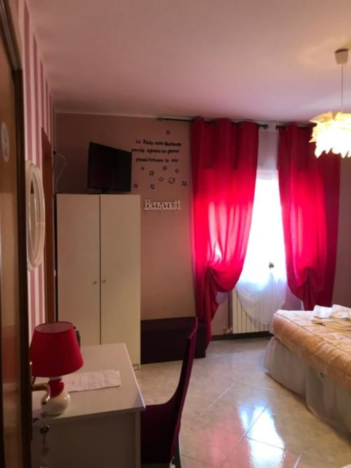 Camera da letto moderna con tende rosse, TV a schermo piatto, armadio e scrivania presso RL GROUP Isernia B&B