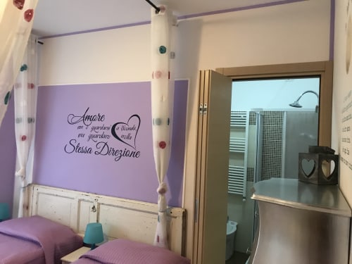 Camera da letto con tema viola presso RL GROUP BnB a Isernia, con arte murale con citazione italiana, bagno en-suite e arredi moderni