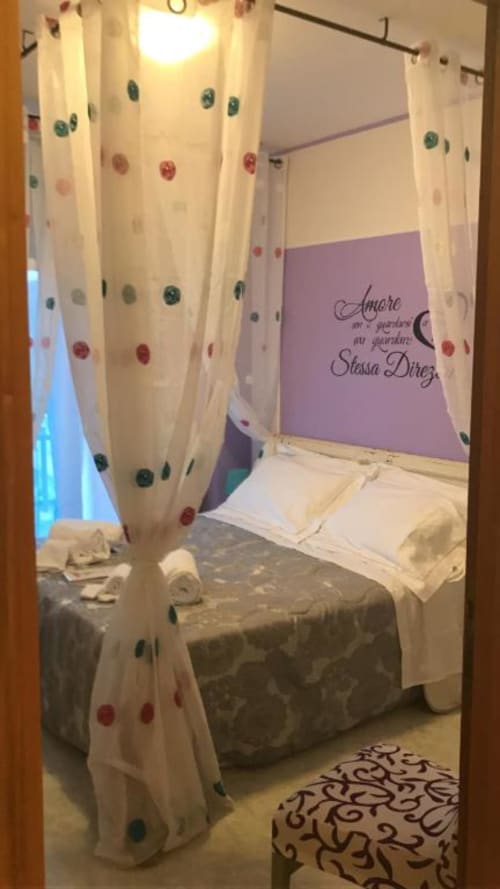 Camera accogliente con tende a pois bianchi, parete accent viola e citazione decorativa presso RL GROUP B&B a Isernia, Italia