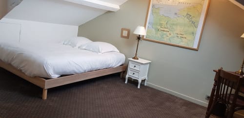 Chambre douillette mansardée à l'hôtel Les Cabines à Houlgate avec lit en bois, literie blanche et décor de cartes vintage