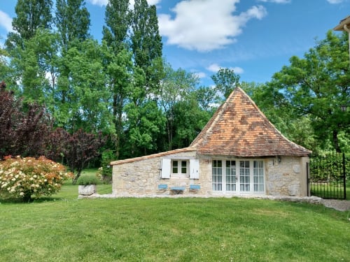 Le Séchoir cottage with conical roof, stone exterior, and garden view at La Barrat B&B in Monmarvès, France