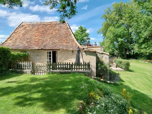 Le Séchoir cottage at La Barrat in Monmarvès with manicured garden, white fence, and stone exterior