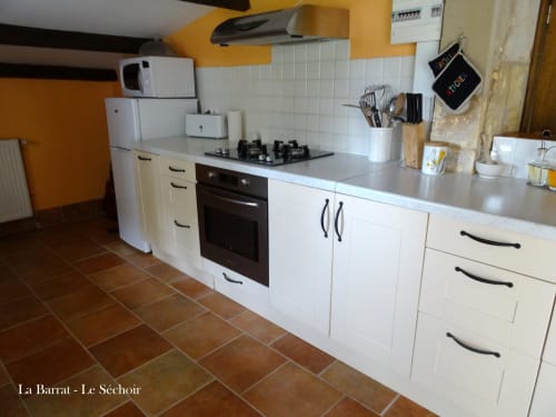 Modern white kitchen with gas cooktop and electric oven in Le Séchoir cottage at La Barrat, Monmarvès