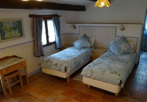 Bright twin bedroom in Le Séchoir cottage at La Barrat B&B, Monmarvès, with blue patterned bedding and garden views