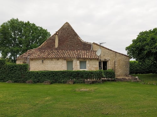 La Crèche cottage at La Barrat B&B in Monmarvès features stone exterior with peaked roof and manicured lawn.