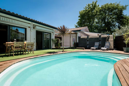 Villa Eden Bleu, vue de la piscine turquoise, terrasse en bois et villa moderne avec espace repas à Biscarrosse