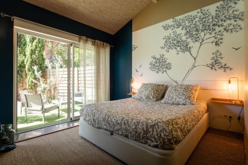 Chambre moderne de la Villa Eden Bleu avec vue sur la piscine, literie à motifs, fresque murale et portes vitrées ouvrant sur la terrasse du jardin