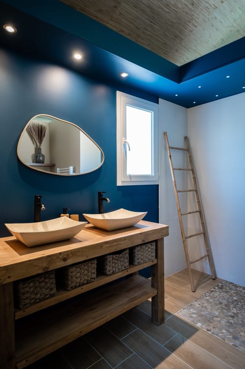 Salle de bains moderne de la Villa Eden Bleu avec deux vasques en bois, murs bleus, miroir mural et échelle en bois à Biscarrosse