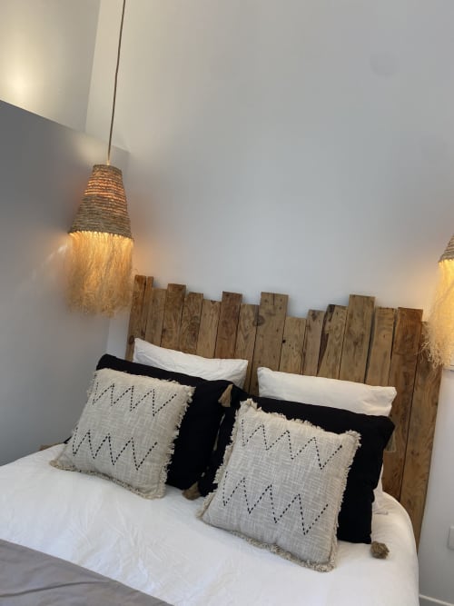 Lit douillet avec tête de lit en bois, oreillers blancs, coussins à motifs et suspensions chez Mas Lafleur, Châteaurenard