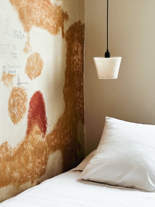 Habitación de hotel moderno en La Prison Béziers con ropa de cama blanca, lámpara colgante y pared de acento texturizada en tonos tierra