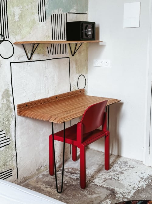 Espacio de trabajo moderno en el Hotel La Prison, Béziers con mesa de madera, silla roja y arte de pared