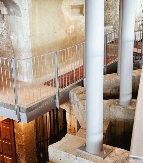 Barandillas metálicas y columnas de apoyo blancas en el corredor subterráneo del Hotel La Prison, Béziers