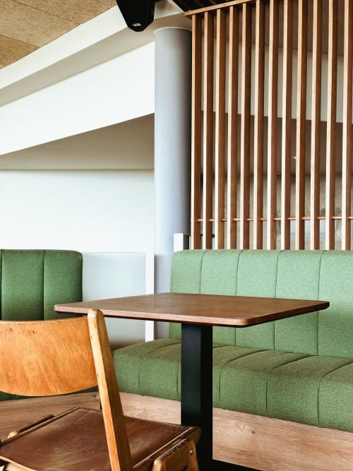 Cabina de comedor moderno en Hotel La Prison Béziers con asiento tapizado en verde, mesa de madera y silla de mediados de siglo.