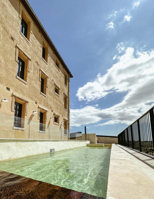 Patio del Hotel La Prison con edificio de piedra, piscina y terraza en Béziers