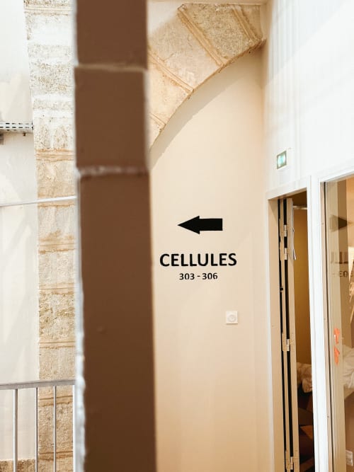 Cartel en el pasillo señalando las celdas 303-306 del Hotel La Prison en Béziers, Francia