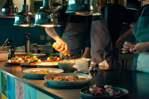 Les chefs préparent des plats de pâtes colorés dans la cuisine de l'Hôtel La Prison à Béziers, France