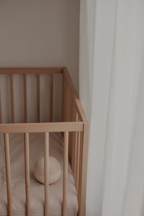 Cuna de madera con ropa de cama blanca en el Hotel La Prison, Béziers