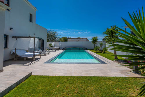Magnífica área de piscina em A Vida é Linda Santa Luzia com água turquesa, deck de madeira, villa moderna branca e palmeiras tropicais