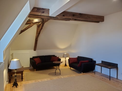 Gezellige zoldersuite in het Logis des Tourelles in Cognac met blootliggende houten balken, zwarte banken en warm licht