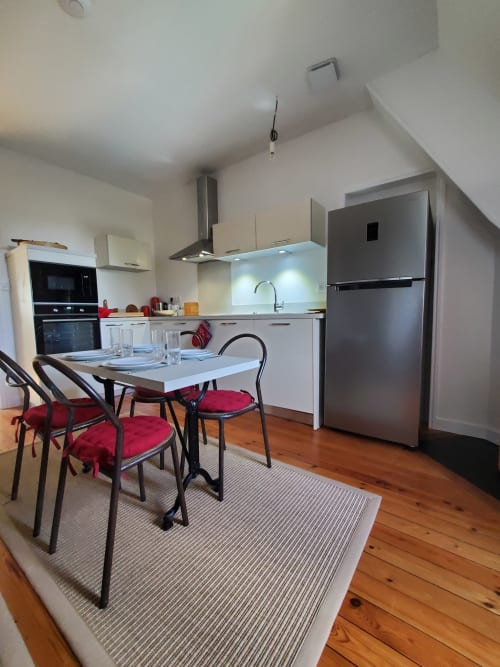 Moderne keuken en eetgedeelte in Logis des Tourelles B&B in Cognac met roestvrijstalen apparatuur en rode stoelen