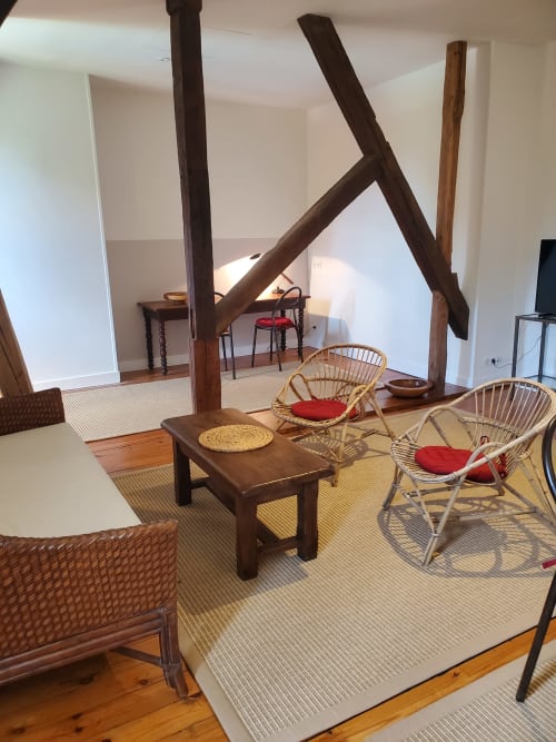 Rustieke lounge bij Logis des Tourelles met zichtbare balken, rotan stoelen en houten meubels in Cognac