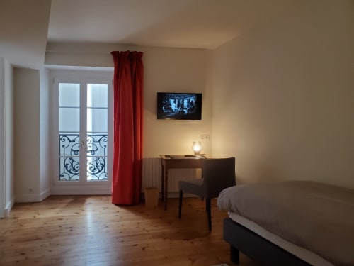 Chambre spacieuse du Logis des Tourelles B&B à Cognac avec parquet, rideaux rouges et équipements modernes.