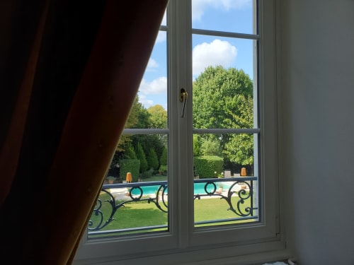 Vue du Logis des Tourelles avec piscine et jardin aux balustrades en fer forgé surplombant les verdoyants jardins de Cognac