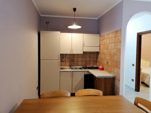 Cucina moderna e zona pranzo nell'appartamento di Civitanova del Sannio con tavolo in legno e mobili color crema