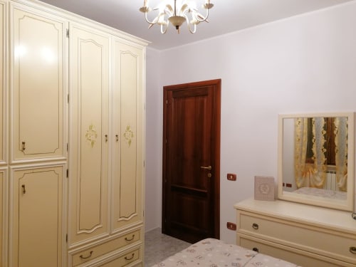 Camera da letto elegante nell'appartamento di Civitanova del Sannio con armadio color crema, specchio e porta in legno scuro