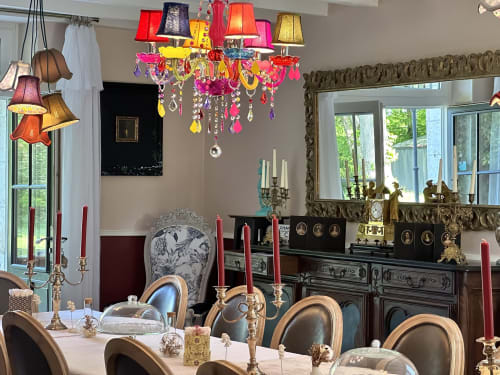 Salle à manger élégante du Manoir Le Coutureau avec lustre coloré, table dressée et miroir orné.