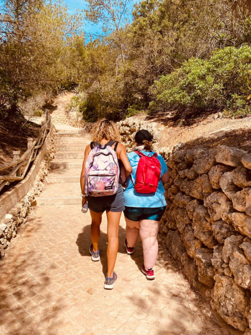 Deux randonneurs en course sur un sentier ensoleillé près de Santa Luzia, avec murs de pierre et végétation méditerranéenne