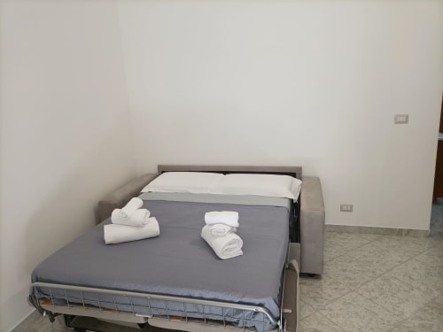 Camera da letto dell'appartamento Newhouse a Bari con divano letto, asciugamani freschi e cuscini bianchi su materasso grigio