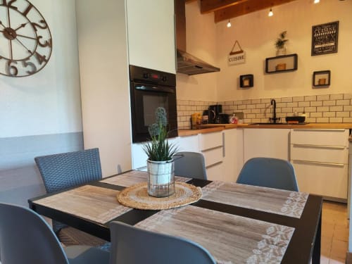 Cuisine-salle à manger moderne du Gîte de la Tannerie à Dinan avec meubles blancs, plan de travail en bois et table de repas bleue