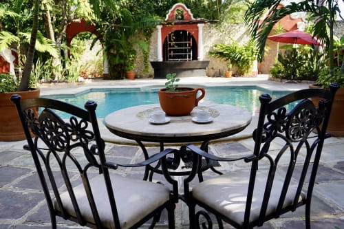 Momentos íntimos junto a la piscina en Villa Mérida Boutique Hotel. La foto muestra una acogedora mesa de café para dos personas junto a la piscina, donde los huéspedes pueden disfrutar de momentos privados en un entorno romántico y tranquilo