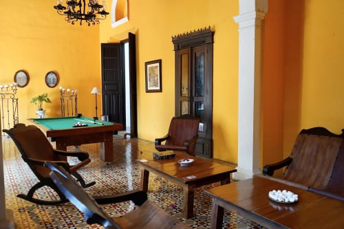 Elegancia colonial en el salón de Villa Mérida Boutique Hotel. La foto captura la acogedora sala de estar, con tumbonas y una mesa de billar, que evoca un ambiente atemporal de sofisticación y relajación