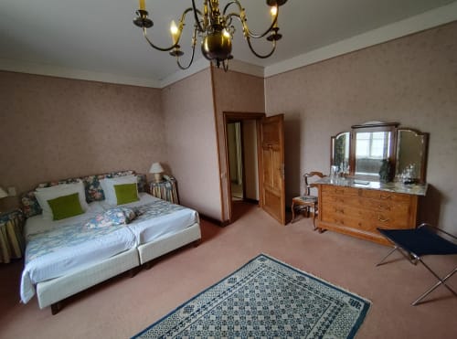 Chambre spacieuse du Château d'Hassonville B&B à Marche-en-Famenne avec lit, commode en bois et miroir