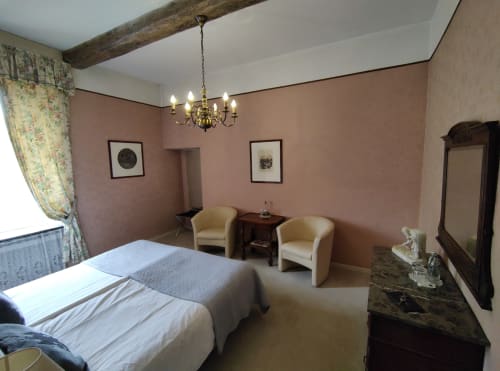 Chambre élégante au Château d'Hassonville aux murs rose, poutres apparentes, lustre, lit et coin détente d'époque