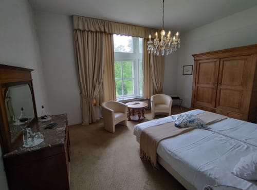 Chambre élégante au Château d'Hassonville avec vue sur le parc, lustre, mobilier en bois et coin détente