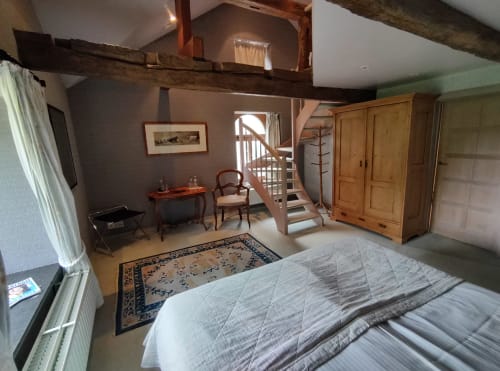 Chambre spacieuse à l'annexe du Château d'Hassonville avec poutres apparentes, lit, armoire et escalier vers la mezzanine