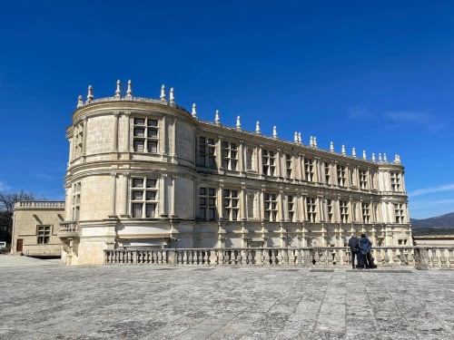 Historic stone château in Grignan with ornate architecture, manicured courtyard, and clear blue sky