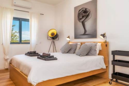 Chambre moderne de la villa A Vida é Linda Santa Luzia avec lit en bois, linge blanc, art abstrait et vue sur le jardin