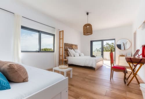 Chambre lumineuse à A Vida é Linda Santa Luzia avec lit queen, coin salon, parquets et vue sur le jardin depuis le balcon
