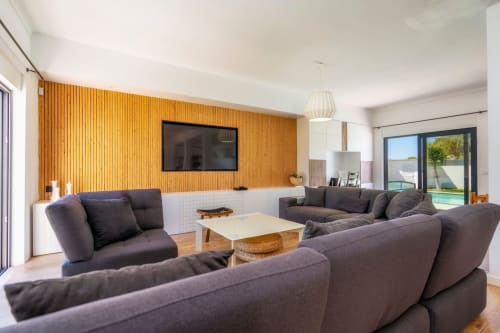 Séjour moderne avec canapés gris, mur en bois, téléviseur et vue sur le jardin à A Vida é Linda Santa Luzia