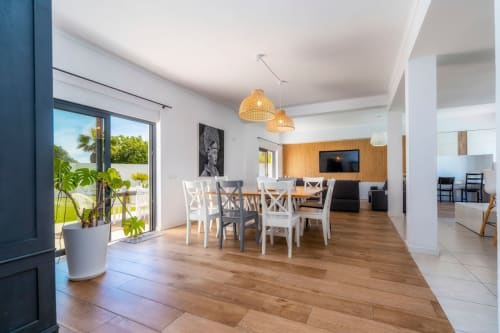 Salle à manger de villa moderne avec vue sur jardin, parquet, chaises blanches, luminaires suspendus et accès à la terrasse chez A Vida é Linda