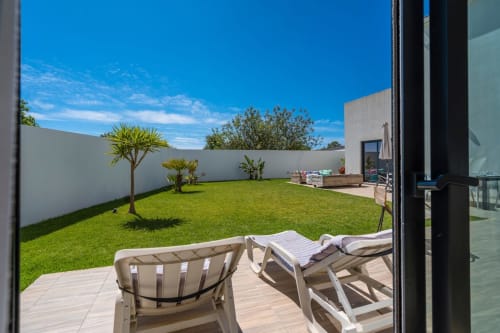 Vue du jardin depuis la terrasse de la villa A Vida é Linda Santa Luzia, chaises longues surplombant une pelouse impeccable