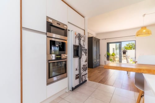 Cuisine moderne à la villa A Vida é Linda avec électroménagers en acier inoxydable, placards blancs, plan de travail en bois et vue sur le jardin