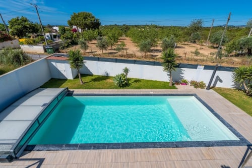 Villa moderne avec piscine aux eaux turquoise, terrasse en bois, murs blancs et vue sur la campagne de Santa Luzia, Portugal