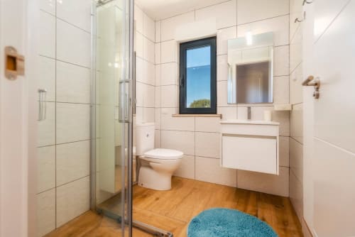 Salle de bains moderne avec douche ouverte, carrelage blanc, parquet et vue sur le jardin à A Vida é Linda Santa Luzia